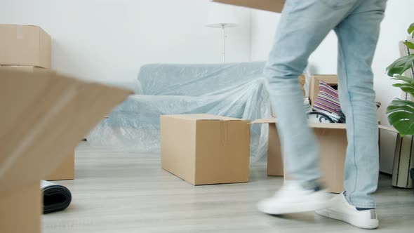 Low Shot of Man Brunet Walking Indoors Bringing Cardboard Boxes to New Apartment