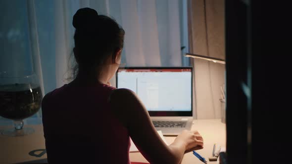 Girl Does Homework in the Evening, Uses a Laptop