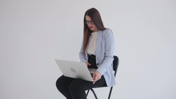 Strong Confident Business Ledy in Black Glasses Sitting with Laptop on Her Lap on White Isolated