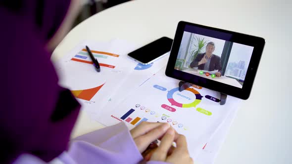 Muslim female worker conference video call on tablet talks with Businessman working through document