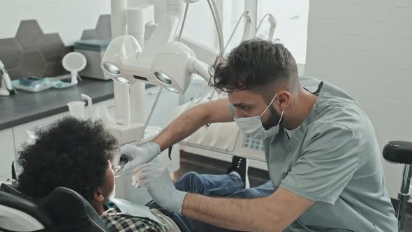 Dentist Treating Boy in Medical Office