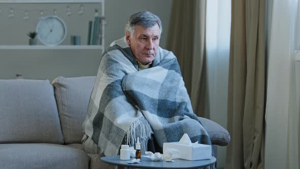 Ill Caucasian Elderly Grandpa Sit in Covered with Blanket on Couch at Home with Cold Remedy
