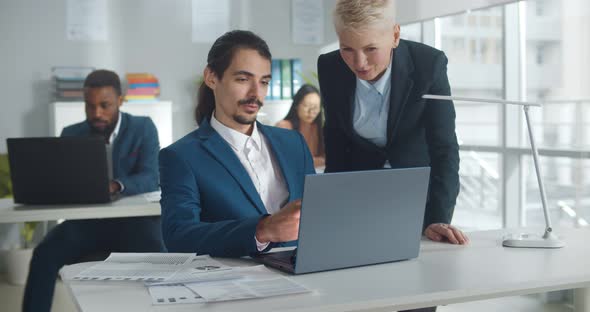 Businessman and Businesswoman Working Together in Creative Office Using Laptop