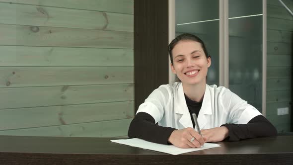 Beauty Salon Receptionist Filling in Form and Greeting Customers with a Happy Smile