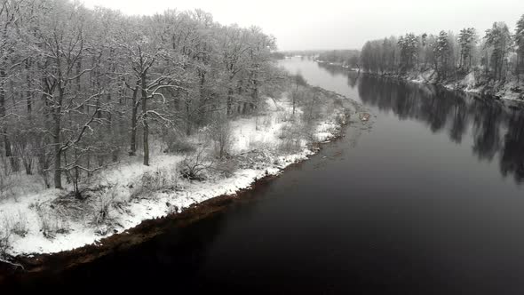 Aerial View of Frozen Trees Standing on the Bank of a Cold River in Winter