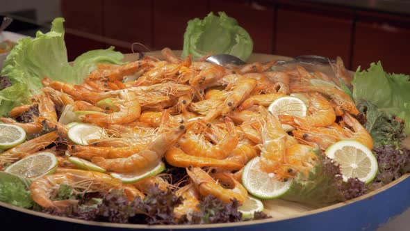 A large dish full of cooked shrimps with lemon and lettuce leaves