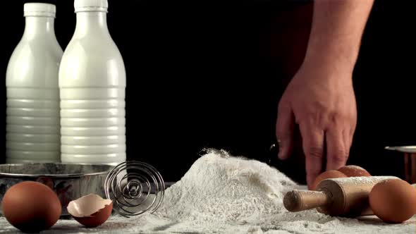 Super Slow Motion Raw Egg Falls in a Pile of Flour on the Table