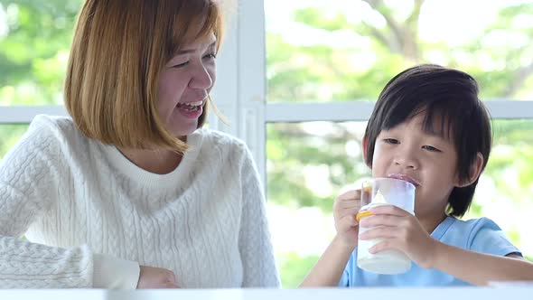 Asian Child Showing Thumb While Drinking Milk With His Mother