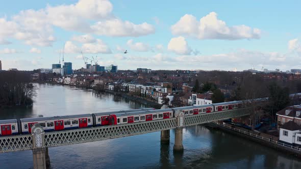 Dolly back drone shot of District line London underground train on Kew Railway bridge