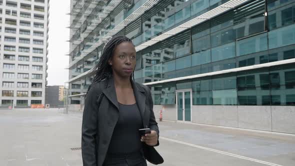 Confident serious black american businesswoman walking in the street -slow motion