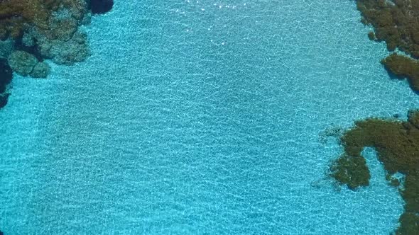 Aerial drone slow top down zoom in on a lagoon with clear blue tropical waters