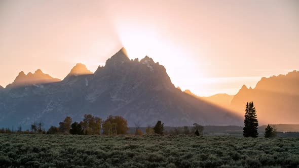 Time lapse of sun rays beaming from behind the Grand Teton Mountains