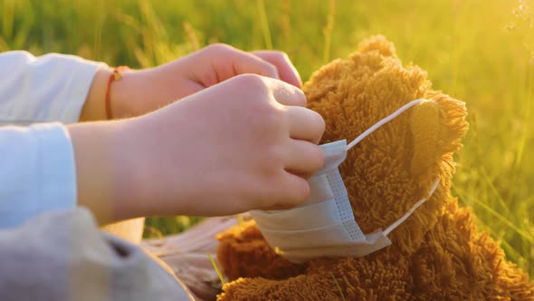 Children's Hands Put on a Protective Mask on the Teddy Bear