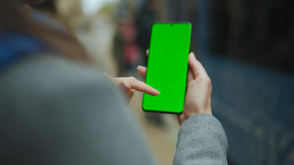 Woman at the Street Using Smartphone with Green Mockup Screen in Vertical Mode