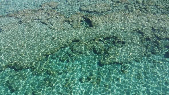 Top view of transparent shallow turquoise ocean sea water surface and rock