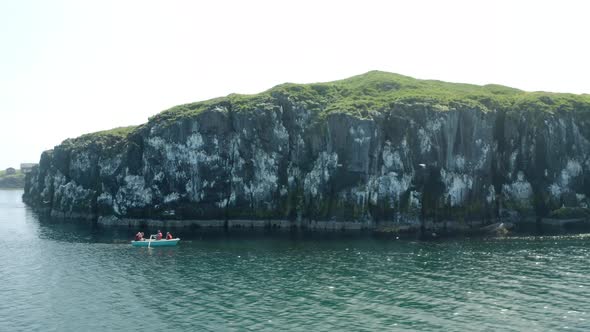 Rocky Cliffs With Tourist Rowing Near Flatey Island, Breidafjordur Bay, Iceland. Aerial Drone Orbit