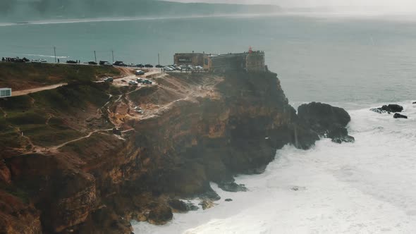 Lighthouse on Steep Cliff Near Ocean on Rainy Day Aerial