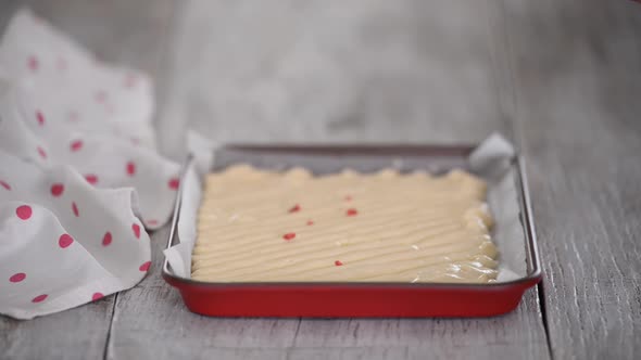 Pastry Chef Hands Sprinkle a Frozen Raspberries on Cake Batter