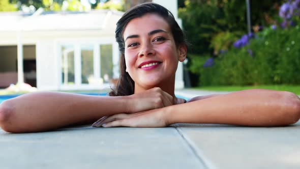 Woman smiling while leaning over the swimming pool