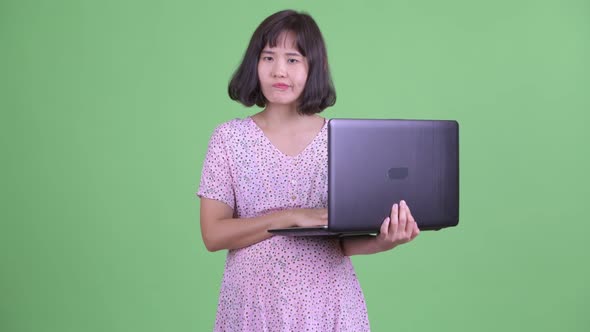 Happy Asian Pregnant Woman Thinking While Using Laptop