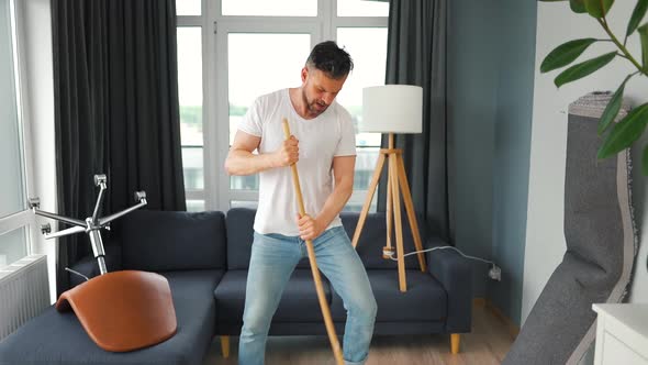 Man Cleaning the House and Having Fun Dancing and Singing with a Broom