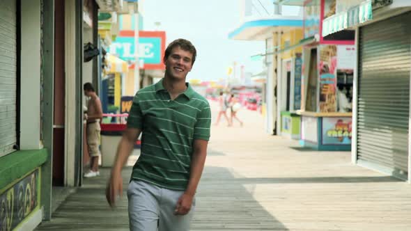 Teenage boy waving and walking on pier