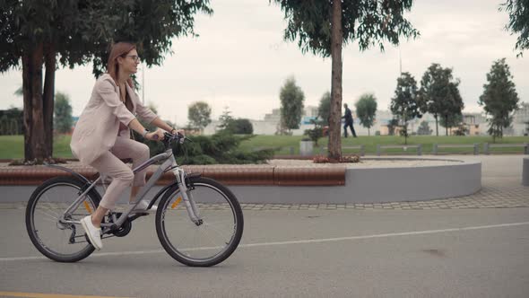 Happy Smiling Woman Is Riding a Bike in Cloudy Summer Day in Park