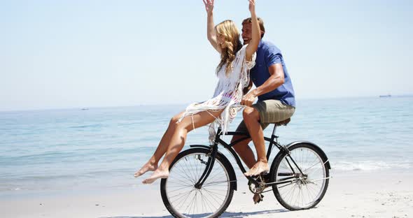 Happy couple riding bicycle at beach