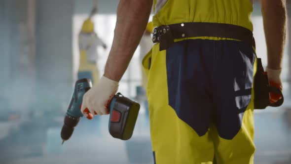 Close Up of Builder Holding Screwdriver Working at Construction Site
