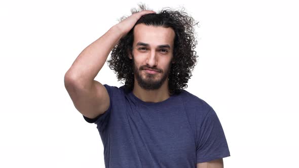 Portrait of Brazilian Guy in Basic Clothing Smiling and Touching His Curly Dark Hair Isolated Over