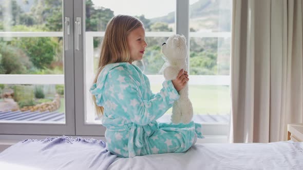 Girl playing with teddy bear on bed 4k