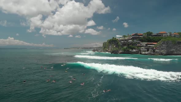 Drone view of lots of people doing surf in the south coast of bali waiting to catch the perfect wave