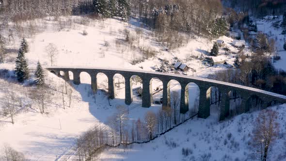 Stone train viaduct above a small village in winter,snow countryside.