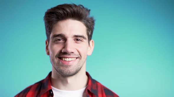 Handsome European Man with Trendy Hairdo in Red Plaid Shirt on Blue Studio Background. 