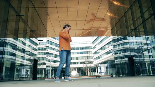 A Lady Is Listening To Music Near Modern Urban Buildings