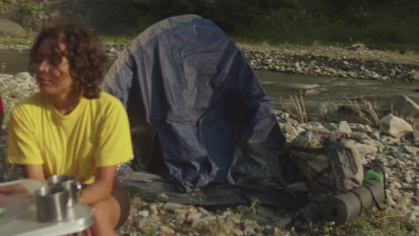 Cheerful Multicultural Women Travelers Preparing Camping Food at Campsite on Mountain Hiking