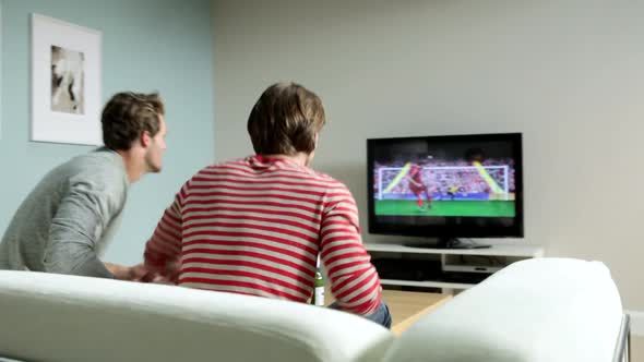 Two young men watching football on television