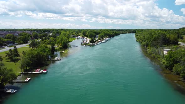 Aerial forward flight over beautiful river surrounded by parking boats during sunny day in Niagara F