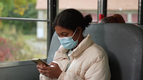 Masked Mixed Race Girl Using Phone in School Bus