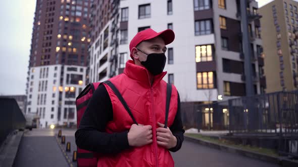 Delivery Guy Wearing Red Uniform While Walking Along Modern Buildings Down City Street with Thermal