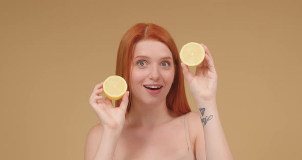 Young Woman with Tattoos on Hand Plays with Lemon Cut Haves