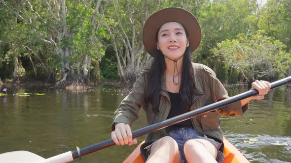 Asian young attractive tourist woman rowing kayak alone in forest lake on holiday vacation.