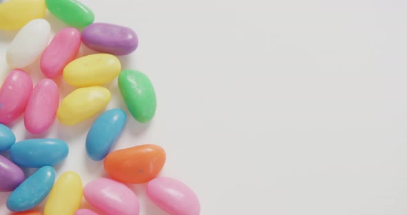 Video of close up of multi coloured sweets with copy space over white background