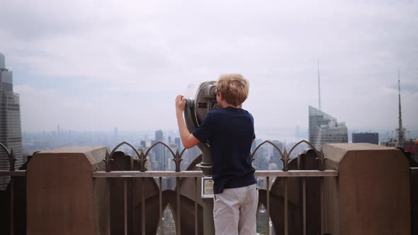 Boy Looking Through Telescope To View New York Skyscrapers