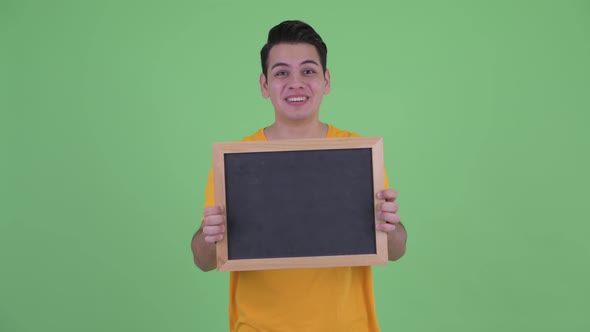 Happy Young Multi Ethnic Man Holding Blackboard and Looking Surprised