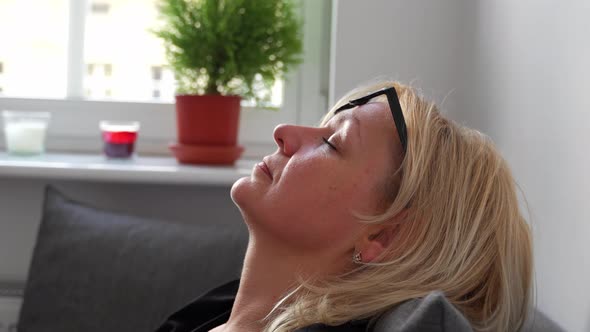 Close Up of Middle Age Woman with Blond Hair Relaxing on the Sofa