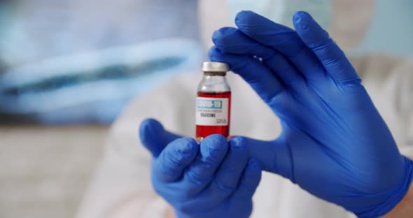 Doctor's Hand Holds Red Ampoule Vaccine Bottle at the Hospital