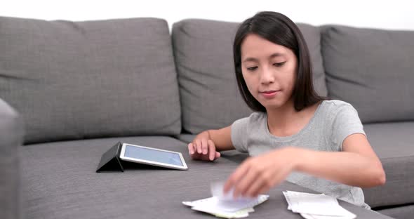 Woman record the daily expense of tablet computer at home