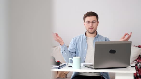 Calm Young Man Relaxing with Laptop in Yoga Position