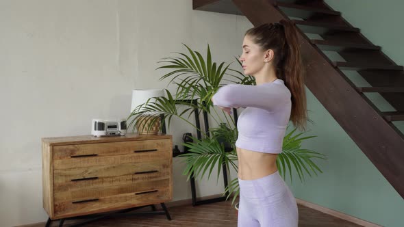 a Woman in a Tight Purple Suit at Home Does Spinal Twists in the Chest Area